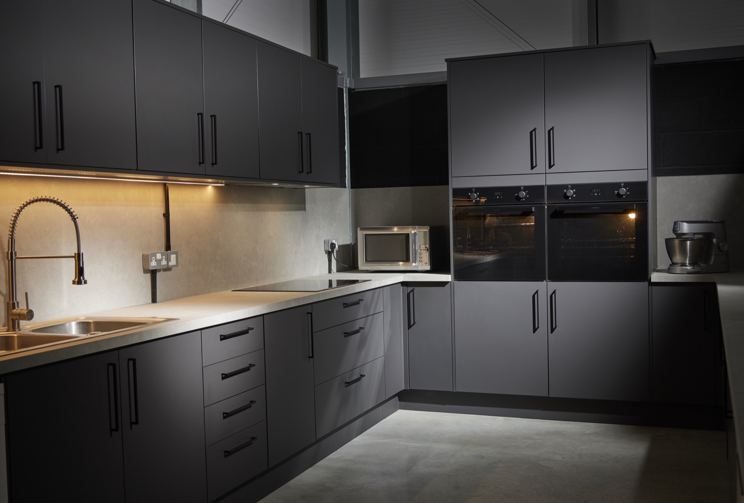 The Hopclover production kitchen: graphite units, stone worktops, twin sinks and pro spray tap